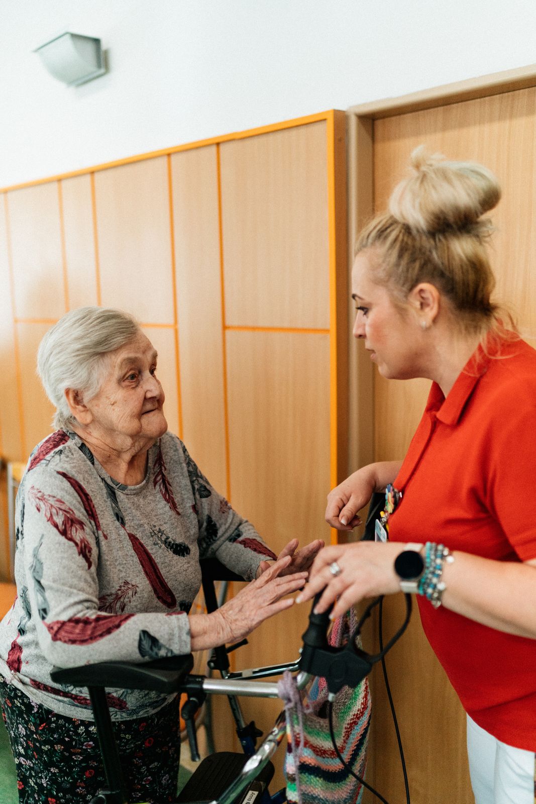 A smiling caregiver helping an older woman walk with her rollator